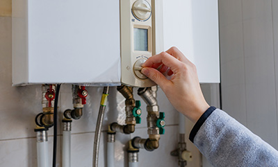 person adjusting the temperature dial on a boiler system ensuring efficient heating with seven essential steps for optimal performance