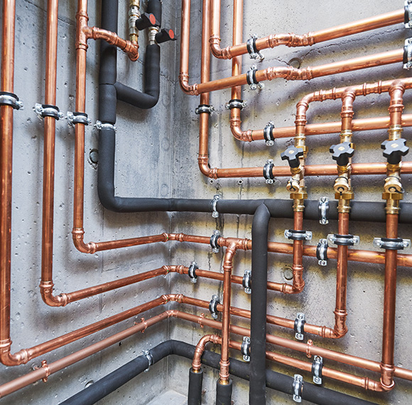 complex network of copper and black plumbing pipes with valves arranged on a concrete wall modern plumbing installation 2 connections and fixtures