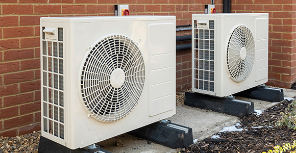 two outdoor air conditioning units installed against a brick wall in a residential setting energy efficient cooling system for home comfort 11 models available