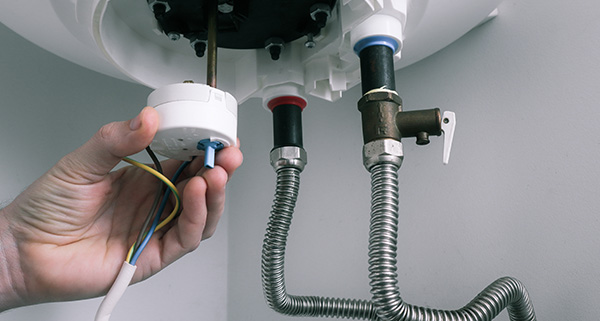 person installing a water heater with wiring and connections for two pipes and electrical components 17 water heating systems installations