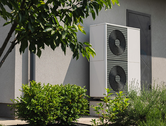 modern heat pump unit installed outside a house surrounded by greenery offers energy efficiency solutions for homes achieving savings of up to 10 percent