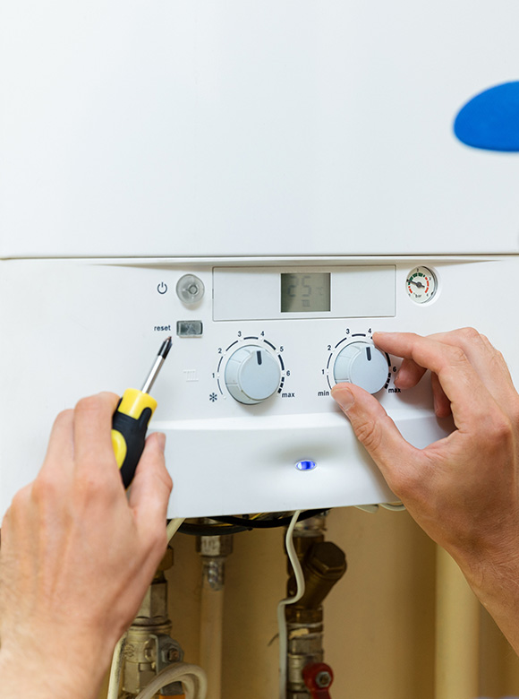 person adjusting a thermostat on a boiler with a screwdriver showing settings for temperature and flow managing heating systems for optimal efficiency at 14 degrees