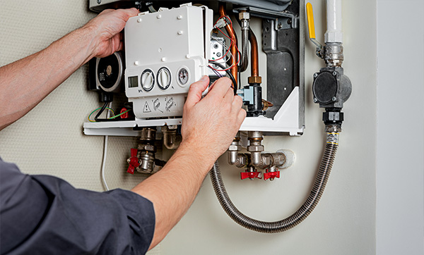 person adjusting a boiler control panel with hands on the device demonstrating 2 essentials for maintenance