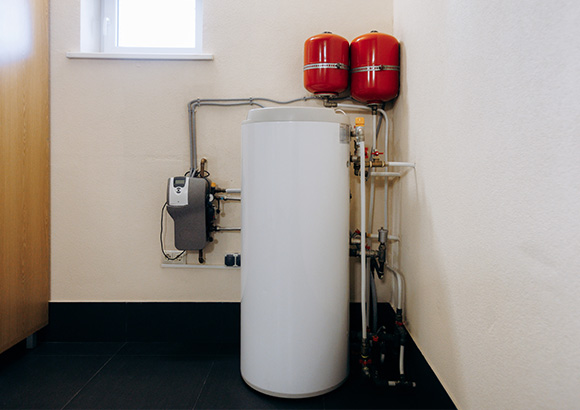 water heater system with pipes and red expansion tanks in corner of room efficiency and maintenance tips for homeowners